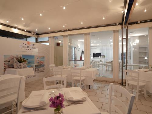 a restaurant with white tables and white chairs at Hotel Rivabella in Davoli