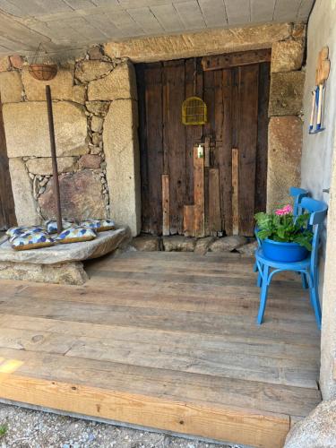 a wooden porch with a blue bench and a door at Casa Las Piedras in Padrenda