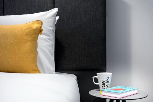 a bed with a yellow pillow and a side table with a cup at Staycity Aparthotels Dublin City Quay in Dublin