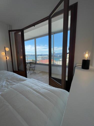 a bedroom with a bed and a view of a balcony at Cosy T3 proche plage. Fibre. Clim in Saint-Mandrier-sur-Mer