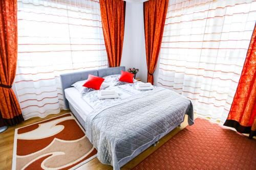 a bed with red pillows in a room with windows at Villa Nadmorska Łeba Centrum in Łeba