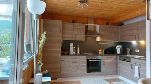 a kitchen with wooden cabinets and a large window at Feriendorf Tauerngast in Hohentauern