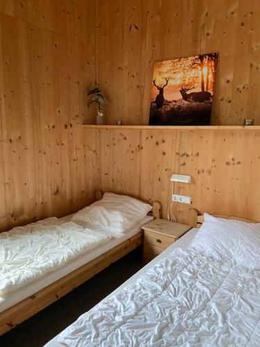 two beds in a room with wooden walls at Feriendorf Tauerngast in Hohentauern