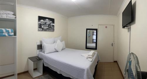 a small bedroom with a white bed and a television at Ncotshane BnB in Pongola