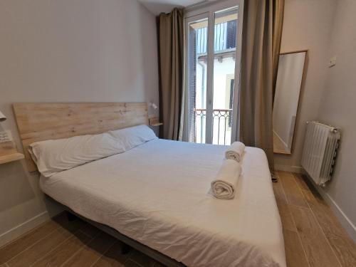a bedroom with a bed with white sheets and a window at Beach Break Guesthouse in Donostia-San Sebastián