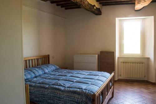 a bedroom with a bed with a blue comforter and a window at Bed and Breakfast La Villa in Fiastra