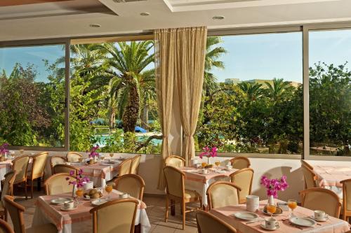 a restaurant with tables and chairs and large windows at Blue Horizon in Ialyssos
