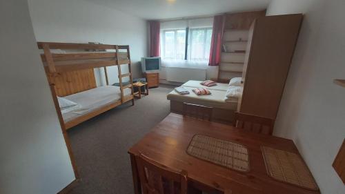 Zimmer mit 2 Etagenbetten und einem Tisch in der Unterkunft Apartmany U Ády in Železná Ruda