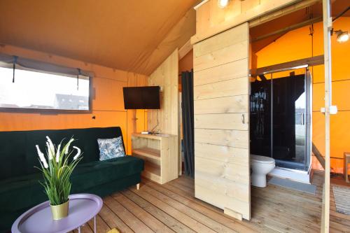 a living room with a green couch and a toilet at Baza Maciejòwka in Międzywodzie