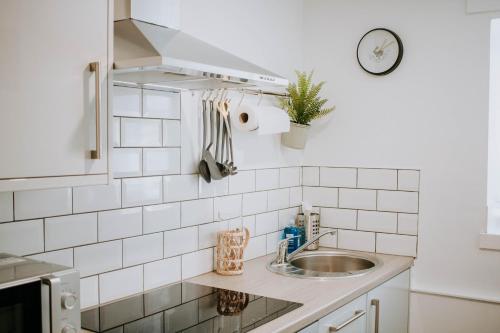 a kitchen with a sink and a clock on the wall at The Bailey - Troon - Coorie Doon Stays in Troon