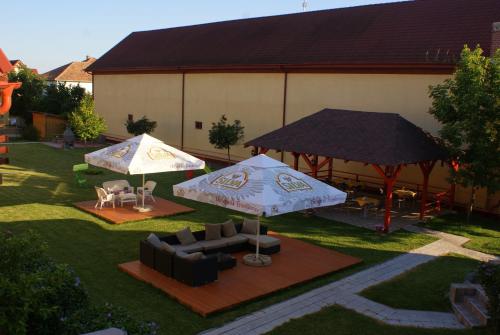 two umbrellas and chairs and tables in a yard at Casa Ardeleneasca in Timişoara