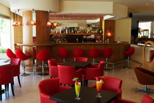 a restaurant with red chairs and tables and a bar at Blue Horizon in Ialyssos