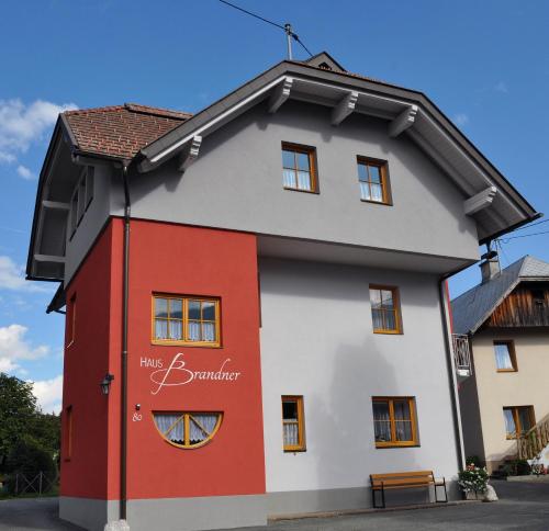 a red and white building with a sign on it at Haus Brandner in Tröpolach