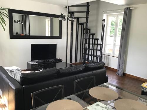 - un salon avec un canapé noir et un miroir dans l'établissement Maison De ville Bayeux, à Bayeux