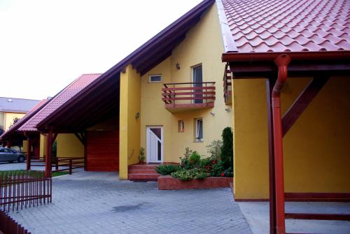 a yellow house with a red roof and a balcony at Casa Ardeleneasca in Timişoara