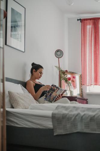 a woman sitting on a bed reading a book at Gallery Apartment 2 in Martin