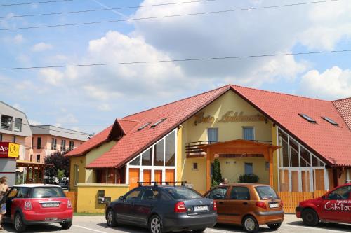 a building with a red roof and cars parked in a parking lot at Casa Ardeleneasca in Timişoara