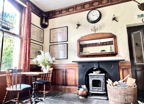 a living room with a fireplace and a clock on the wall at The Buckley Arms in Dinas Mawddwy