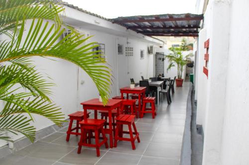 une rangée de tables et de chaises rouges sur une terrasse dans l'établissement Hotel Poblado Suite, à Barranquilla