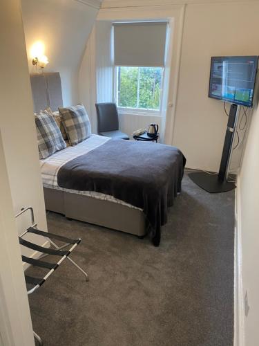 a bedroom with a bed and a flat screen tv at Ellwyn House in Edinburgh