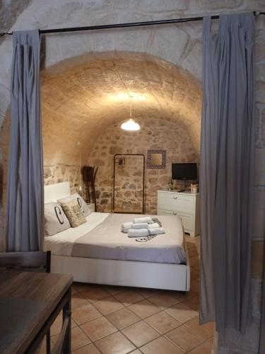 1 dormitorio con 1 cama grande en una pared de piedra en Casa Loredana en Scicli