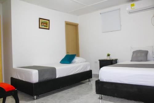 a bedroom with two beds and a red chair at Hotel Poblado Suite in Barranquilla