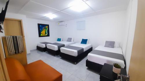 a room with three beds and a couch in it at Hotel Poblado Suite in Barranquilla