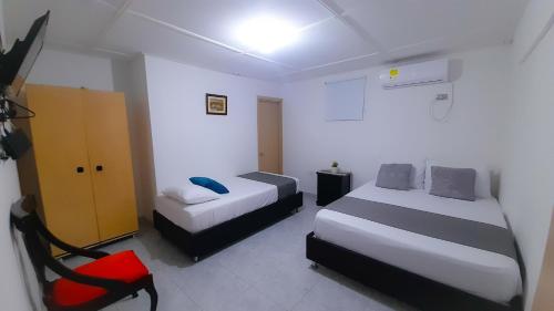 a room with two beds and a chair in it at Hotel Poblado Suite in Barranquilla