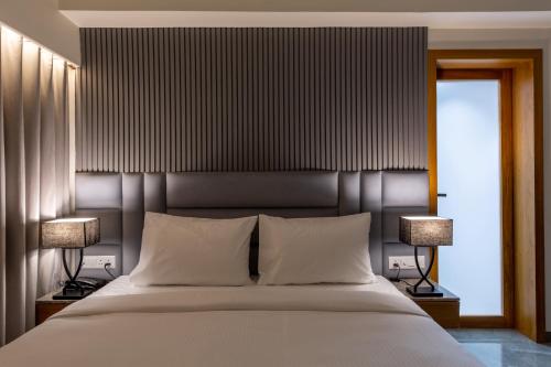a bedroom with a large white bed with two lamps at Hotel Nalanda in Ahmedabad