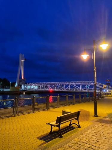 a bench sitting on a sidewalk near the water at night at A Morze Ustka in Ustka