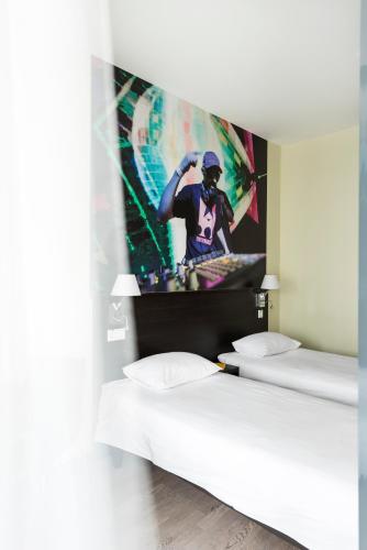 two beds in a room with a tv on the wall at Comfort Hotel LT - Rock 'n' Roll Vilnius in Vilnius