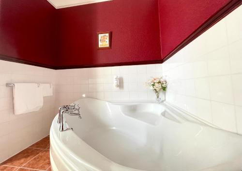 a white tub in a bathroom with a red wall at The Buckley Arms in Dinas Mawddwy