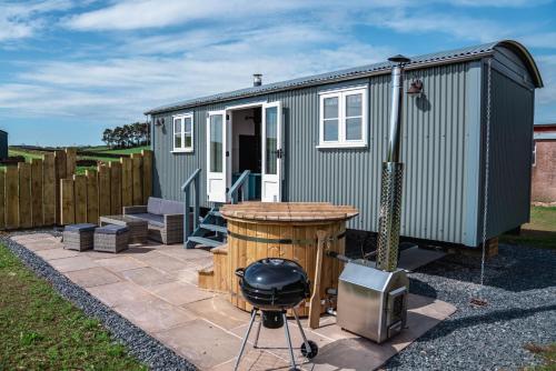 a green tiny house on a patio with a grill at Inglewood Shepherd's Huts in Penrith