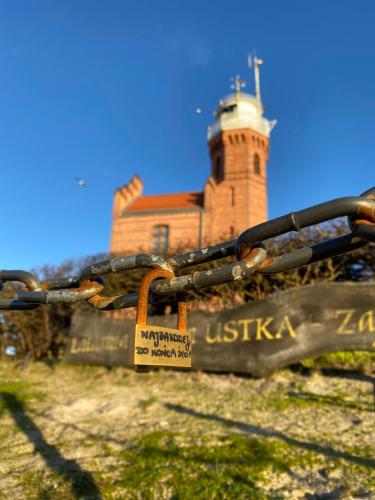 a sign on a gate with a lighthouse in the background at A Morze Ustka in Ustka