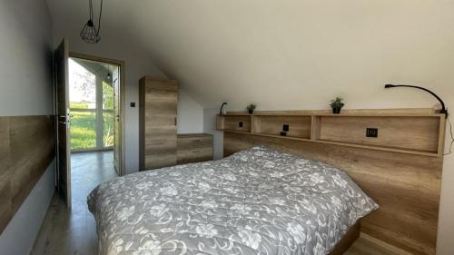 - une chambre avec un lit et un mur en bois dans l'établissement Domek na Roztoczu Obrocz 73C, à Zwierzyniec