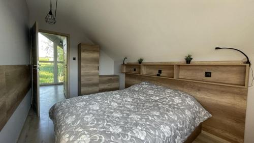 a bedroom with a bed and a wooden wall at Domek na Roztoczu Obrocz 73C z SAUNĄ in Zwierzyniec