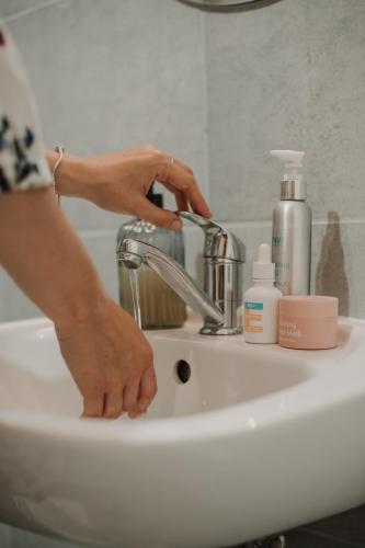 a woman is washing her hands on a bathroom sink at Gallery Apartment 3 in Martin