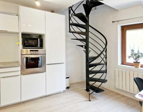 un escalier en colimaçon dans une cuisine avec des placards blancs dans l'établissement Studio, chambres, appartement, gite, à Vendegies-sur-Écaillon