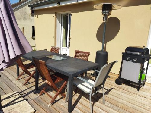 une table et des chaises noires sur une terrasse avec un grill dans l'établissement La chambre secrète, à Longueval