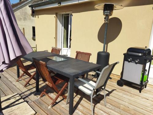 a black table and chairs on a deck with a grill at La chambre secrète des sorciers in Longueval