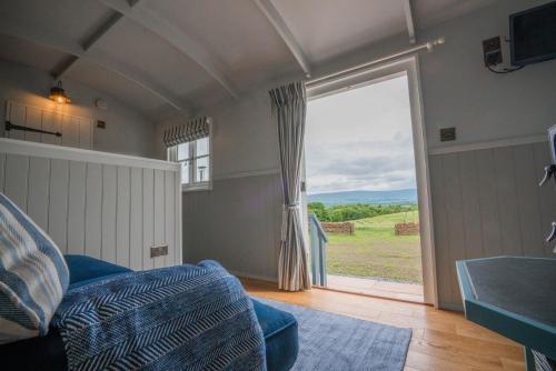 a bedroom with a large sliding glass door with a view at Inglewood Shepherd's Huts in Penrith