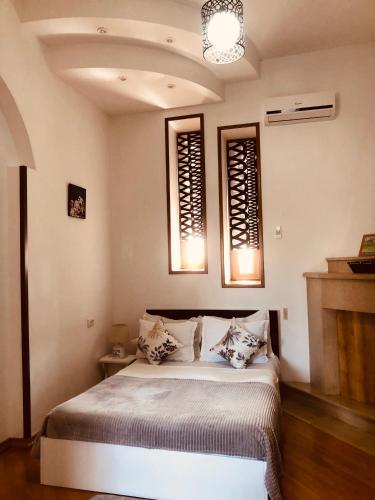 a bedroom with a bed and two windows at Hotel Tamar Mepe in Kutaisi
