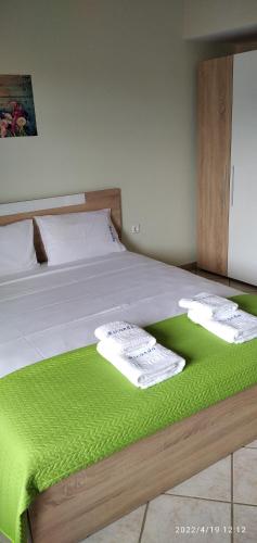 a bed with green sheets and towels on it at Miranda Studios in Paliouri