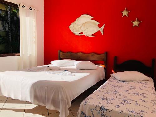 two beds in a room with a red wall at Pousada Casa Do Mar in Paraty