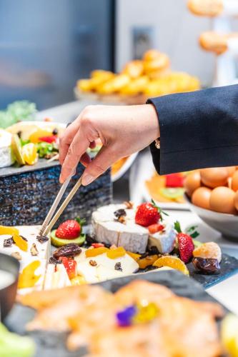 a person holding a knife in front of a buffet of food at Novotel Toulouse Centre Wilson in Toulouse