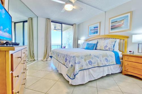 a bedroom with a bed and a tv and windows at Lighthouse Towers 704 in Clearwater Beach