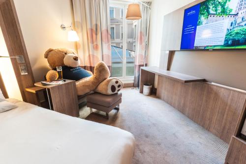 a teddy bear sitting in a chair in a hotel room at Novotel Toulouse Centre Wilson in Toulouse