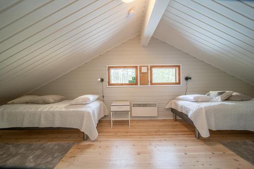 a attic bedroom with two beds and a window at Villa Merino in Kittilä