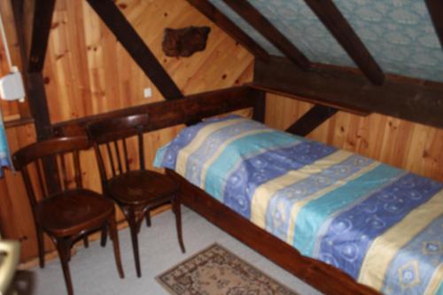 a small bedroom with a bed and two chairs at appartement mitoyen dans chalet in Fraize