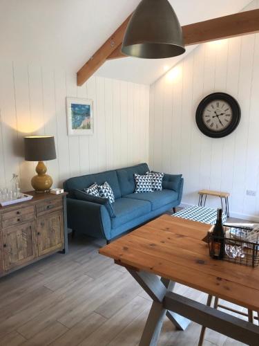 a living room with a blue couch and a clock at The Potting Shed in St Austell